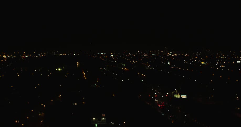 It is pitch black with little light coming from the city below