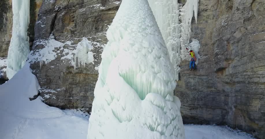 A person is climbing up the cliff covered with ice