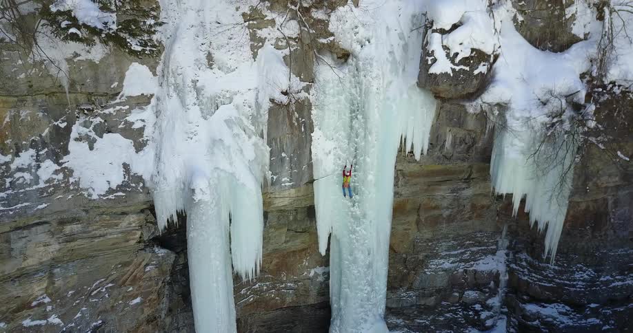A person climbs up an icy cliffside