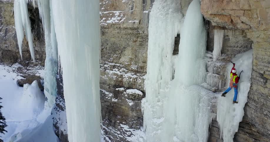 A person climbs an icy cliffside in the wilderness