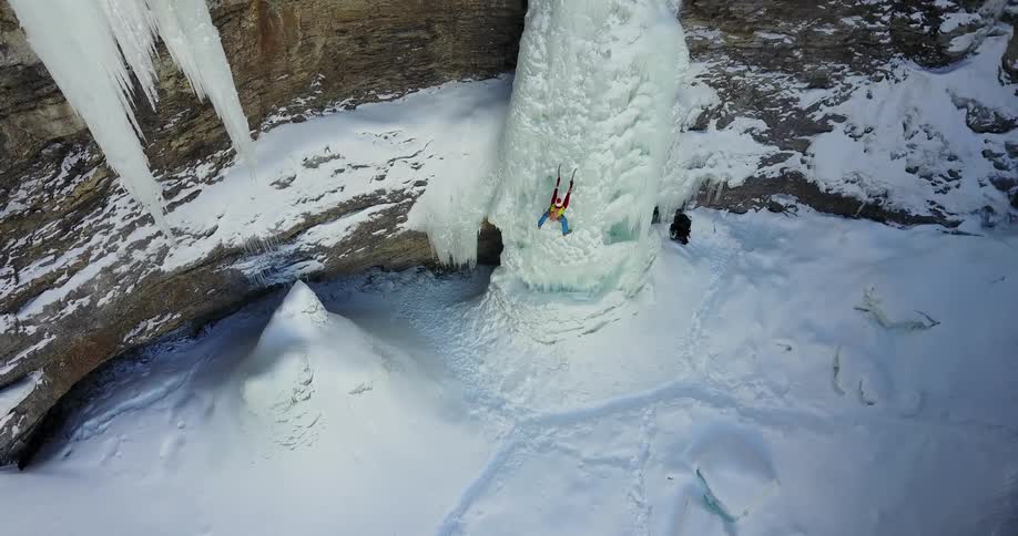A person climbs up an icy cliffside in the wilderness