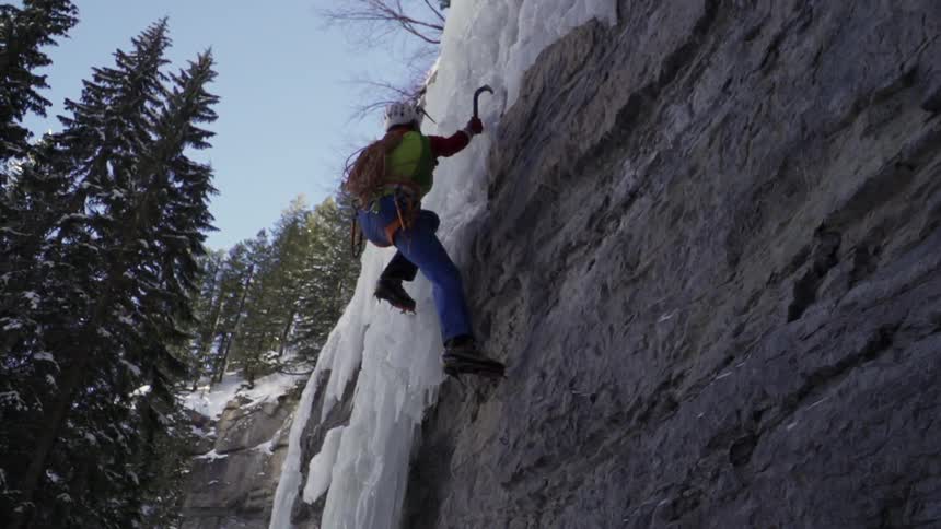 A man is climbing up the cliff covered with ice