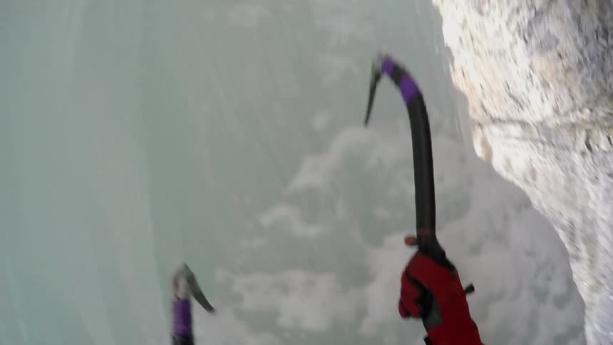 Someone using hooks to climb a wall of ice and snow