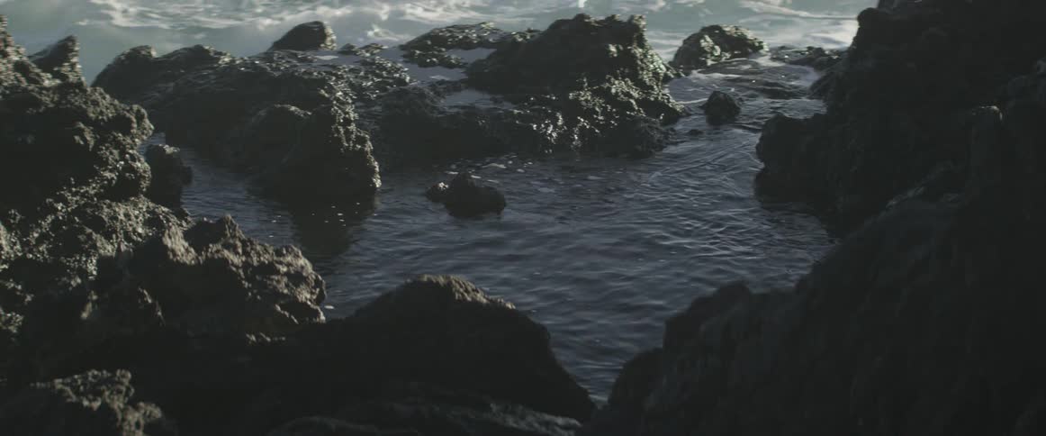The rocks by the shore are being covered with water slowly