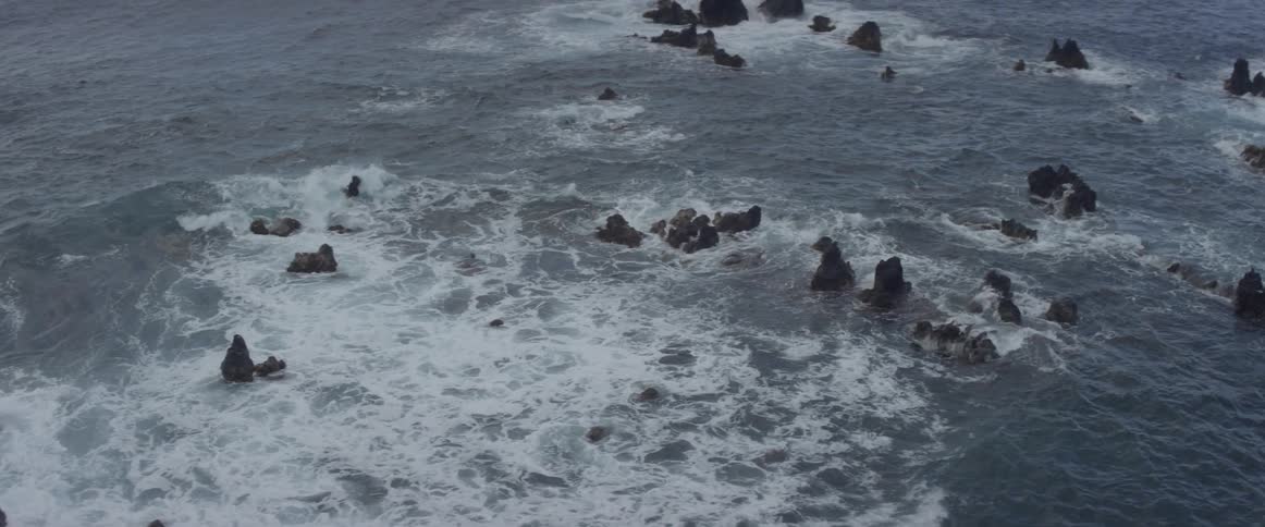 Waves crash and churn around rocks in the ocean