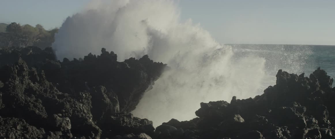 The shore is covered with tall rocks and waves are crashing against them