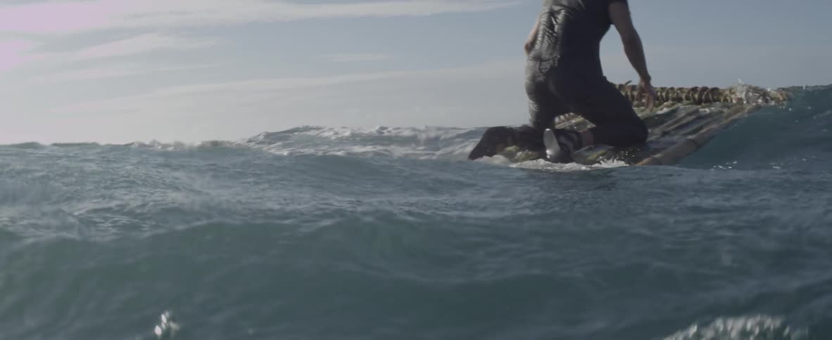 A shipwrecked man floats on debris in the ocean