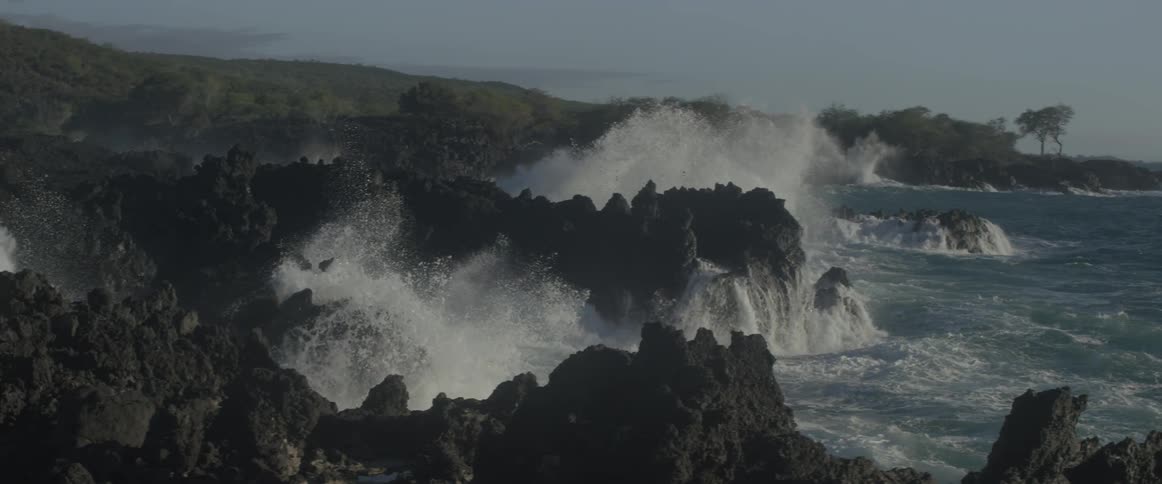 Rough waves crash against jagged rocks