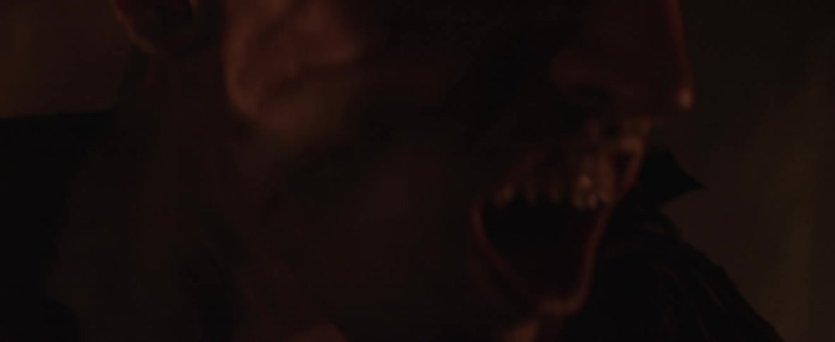 A man with sharp teeth hits something in the dark