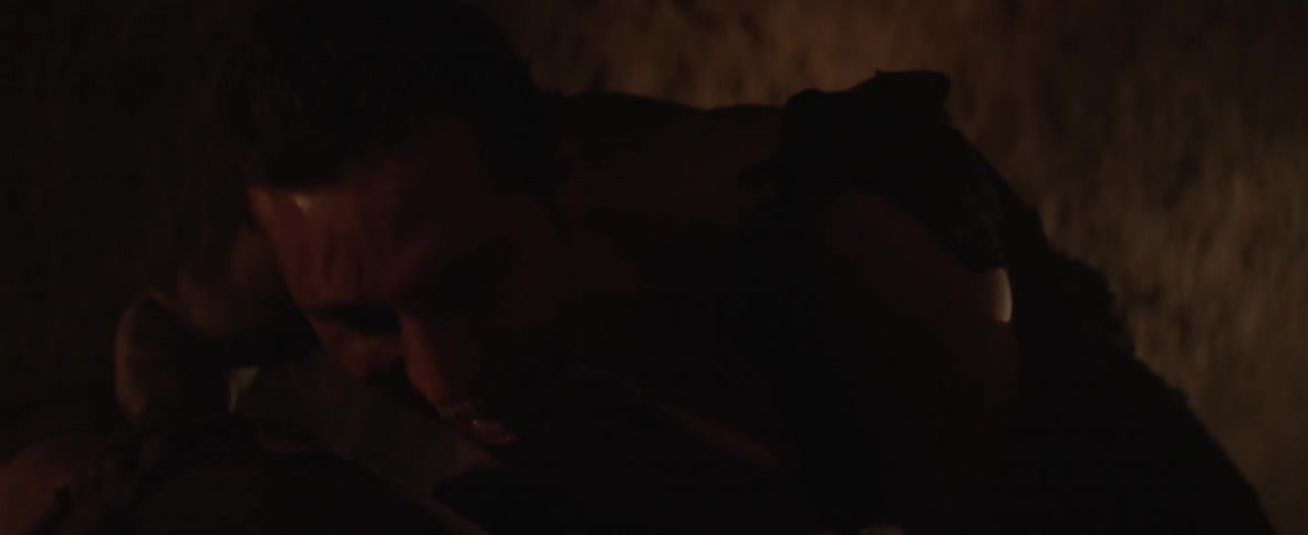 A monster crouches over a chained up prisoner in a dark cave