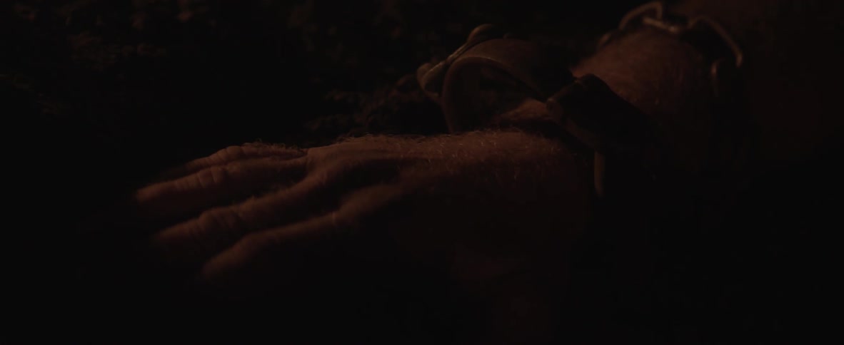 A man is chained up in a dark cave