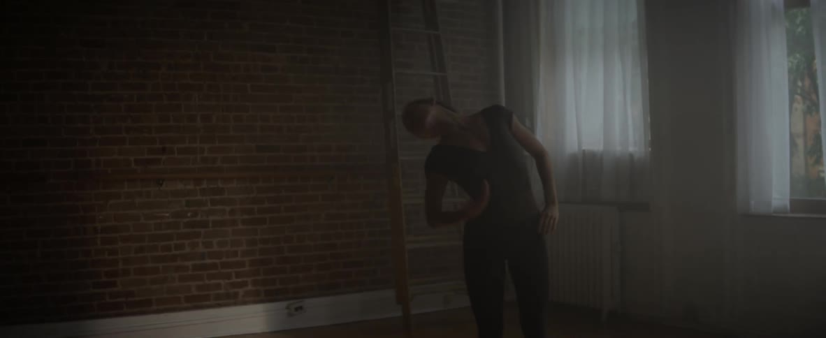 A woman is practicing ballet moves on a wooden floor