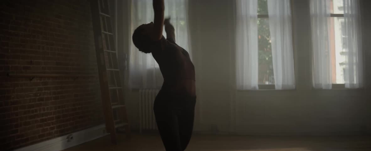 A woman bows forward then begins dancing