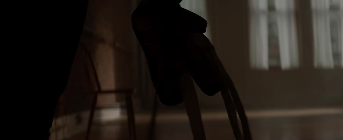 A ballerina carries pointe shoes into a dance studio