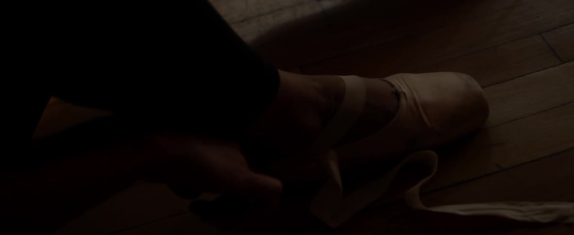 A ballet dancer puts on her shoes
