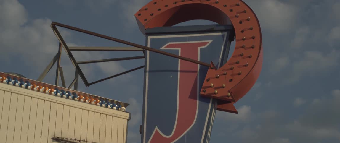 A red circular arrow points to a large sign with a j on it