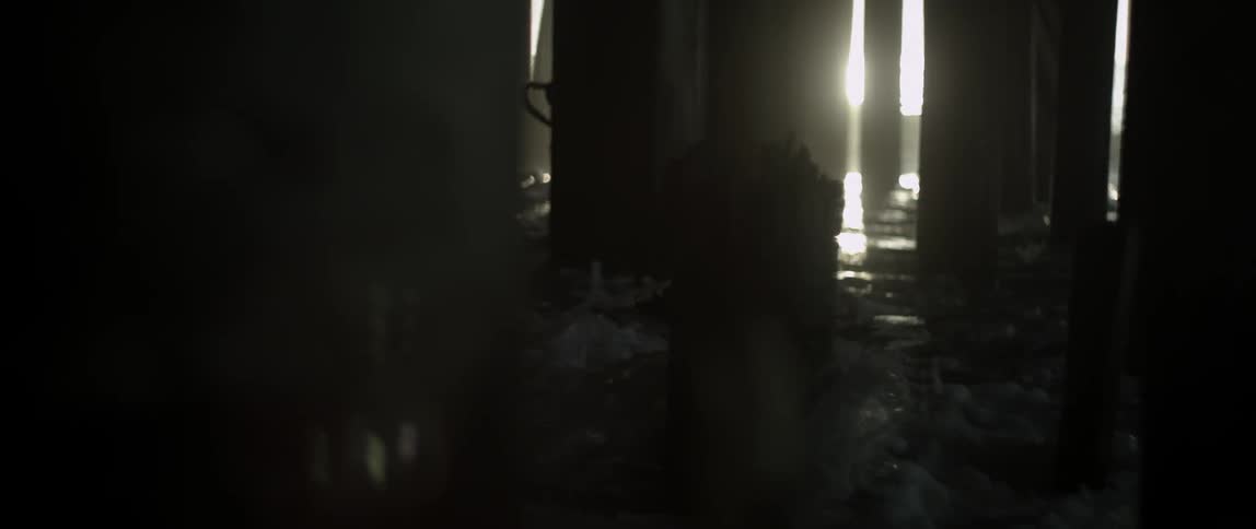 The waves are crashing against the wood under a boardwalk