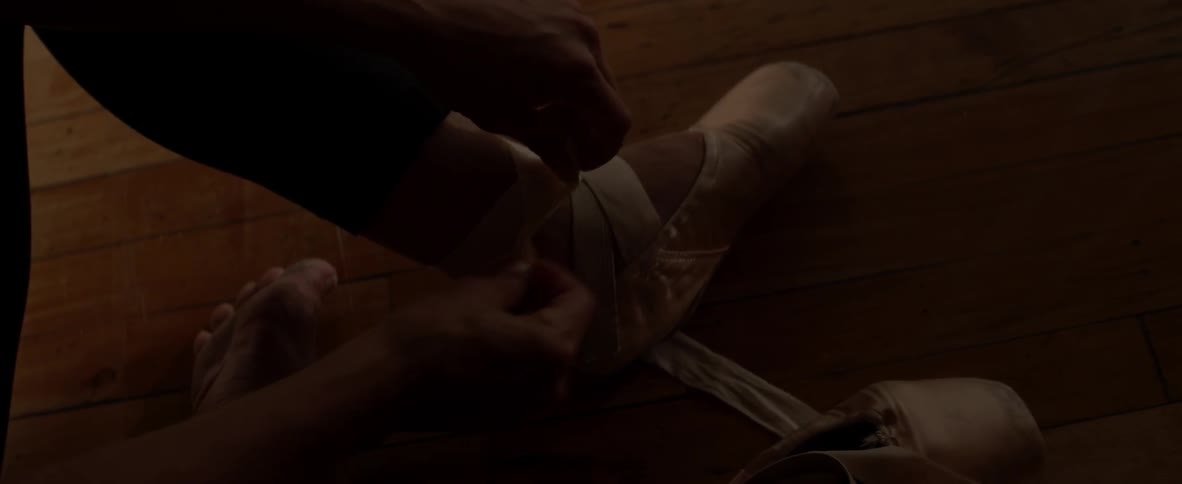 A dancer is lacing up her shoes