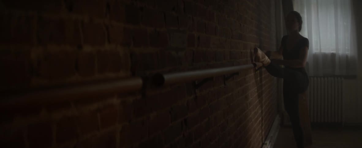 A ballerina stretches against a wall