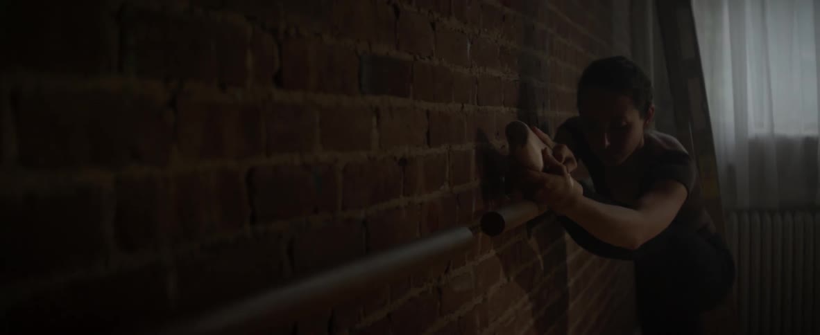 Person feeling their way along a wall in a dimly lit area