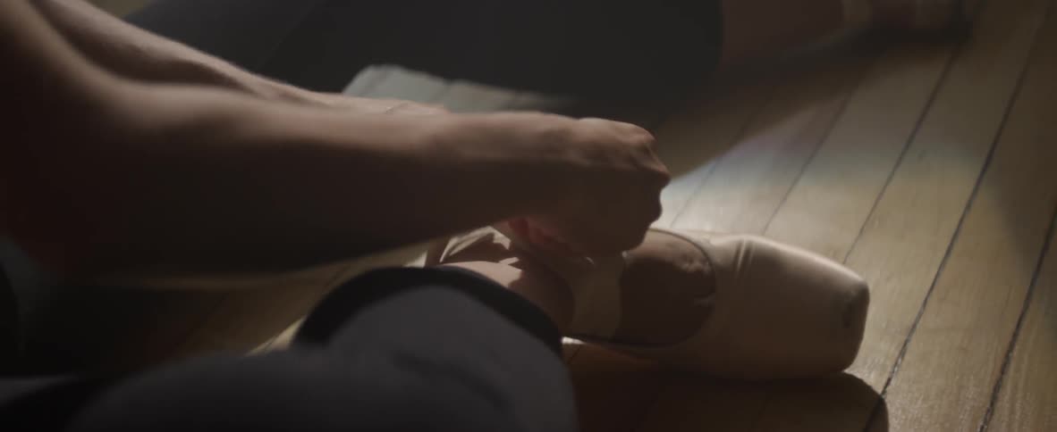 A person is lacing her ballet shoes