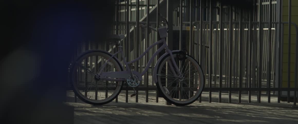 A white bicycle leaning against a fence