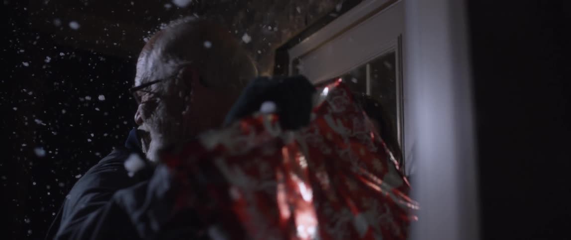 A father happily greets his daughter and son as they arrive at his home on a snowy night during the christmas holidays