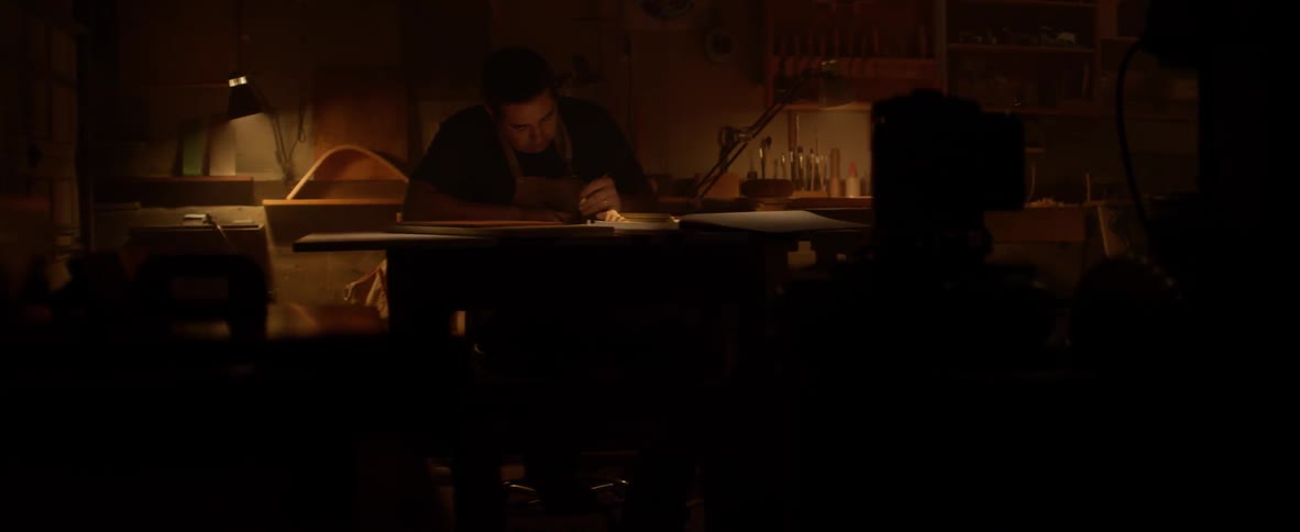 Man writing at a table in a dimly lit area