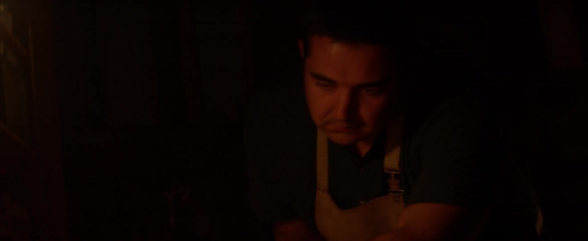 A man is runs his hand along a piece of wood he is working on
