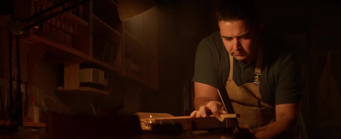 A man uses a hand saw to cut a piece of wood