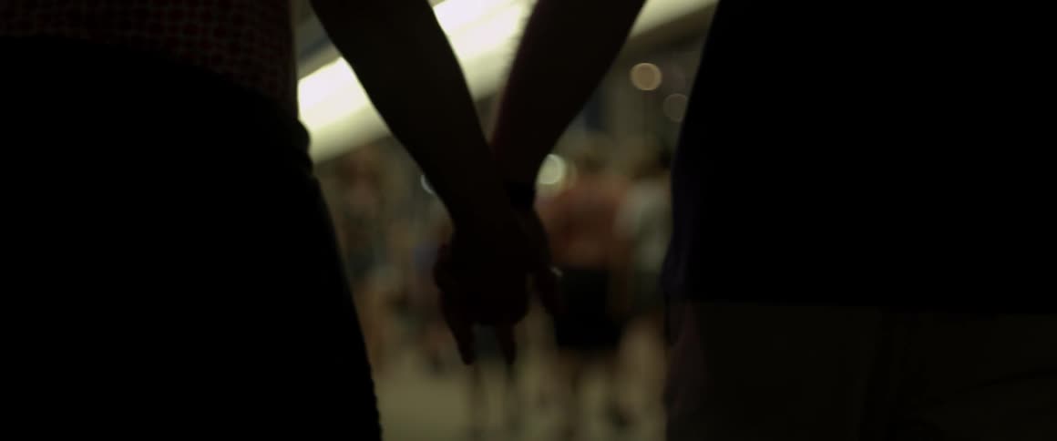 Two people walk at night holding hands