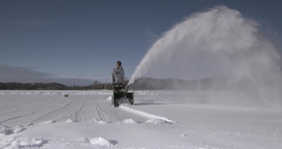 Man pushing a snowblower clearing snow