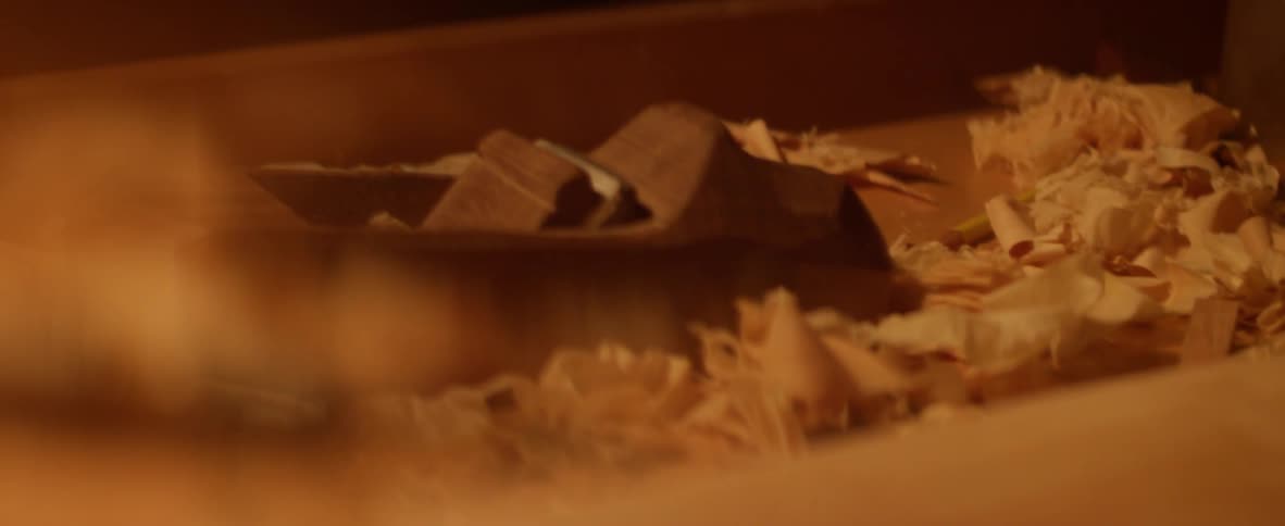 The table is covered with wood shavings and tools