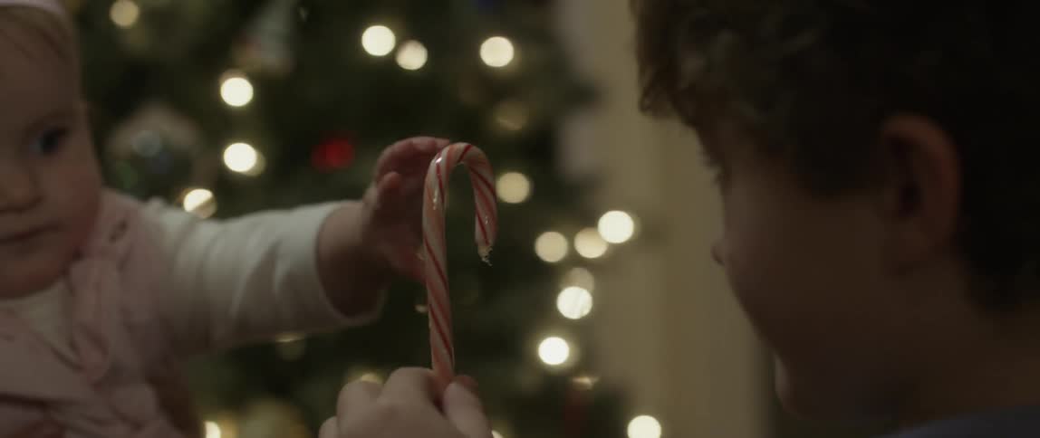 Boy giving baby a candy cane