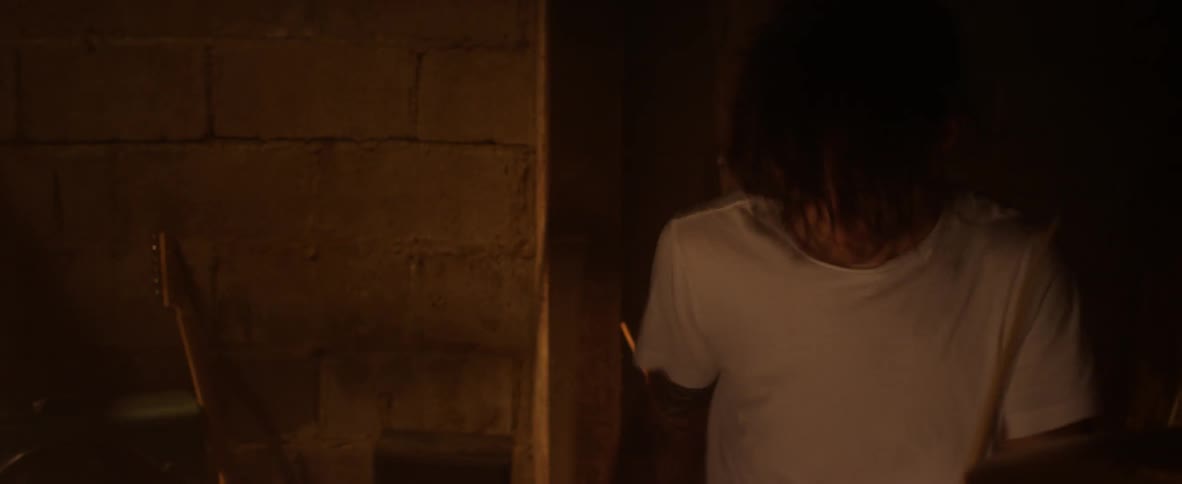 Man plays drums in a dimly lit room