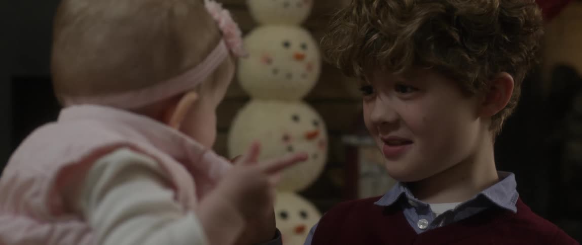 A boy holds a candy cane as he talks with a baby