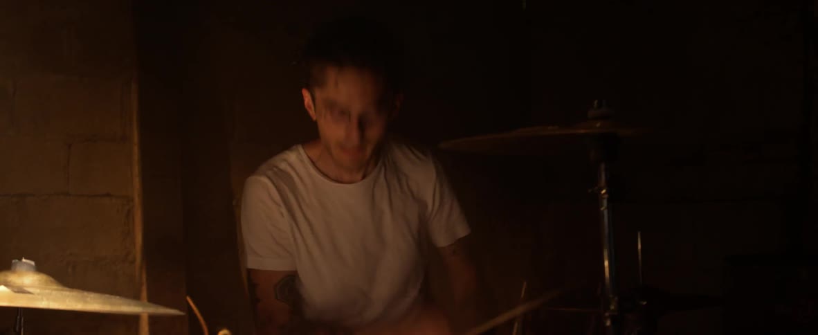 A man in a white shirt plays drums