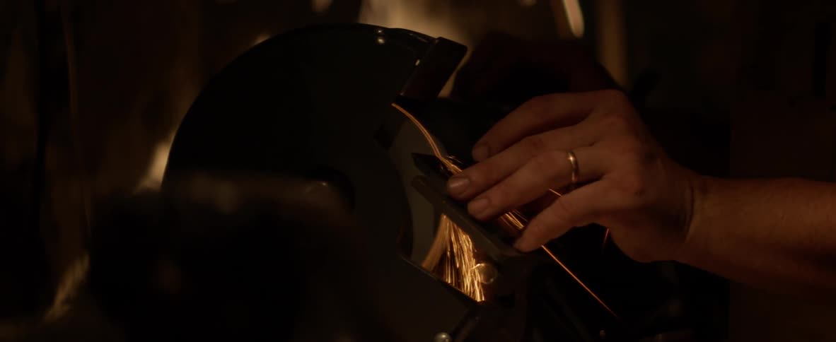 Sparks fly from a grinder as a woman grinds a piece of metal