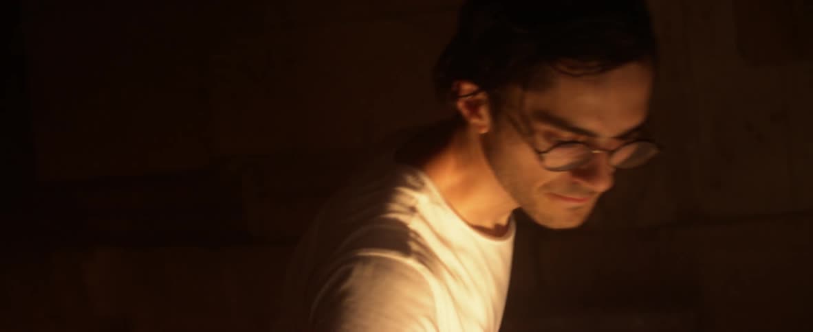 A man walks over to his drums and sits down
