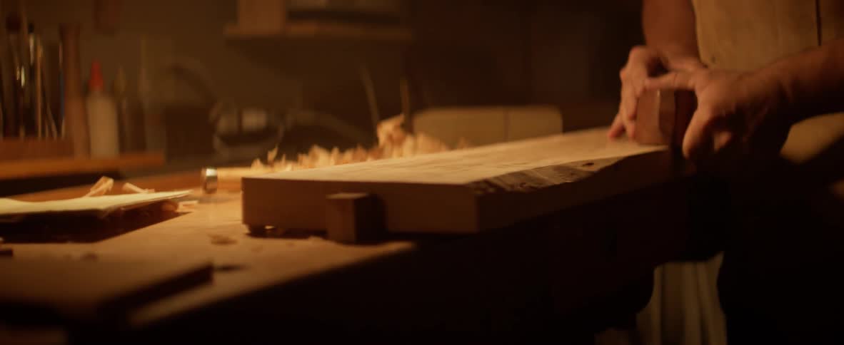 A carpenter smooths a board in a workshop