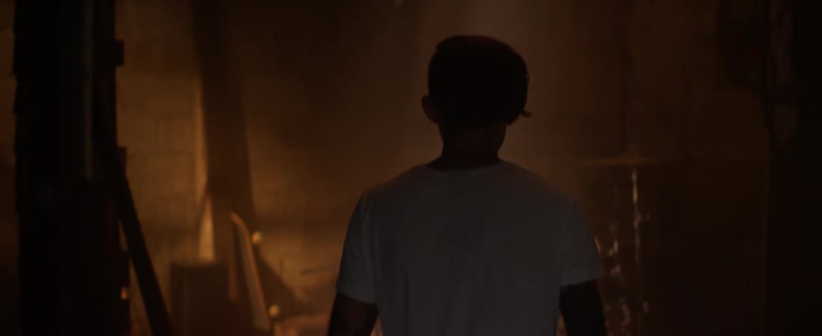 Man walking toward drum set in dimly lit room