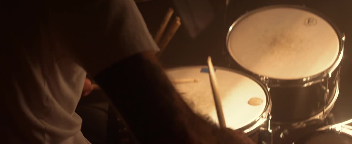 Man beats on a snare drum with drumsticks