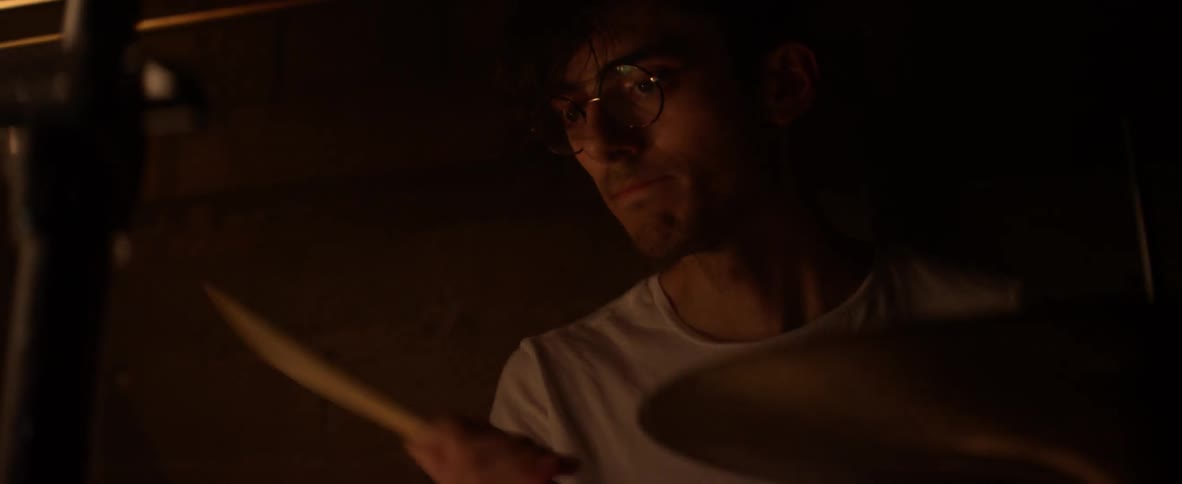 A man plays the drums in a dark room