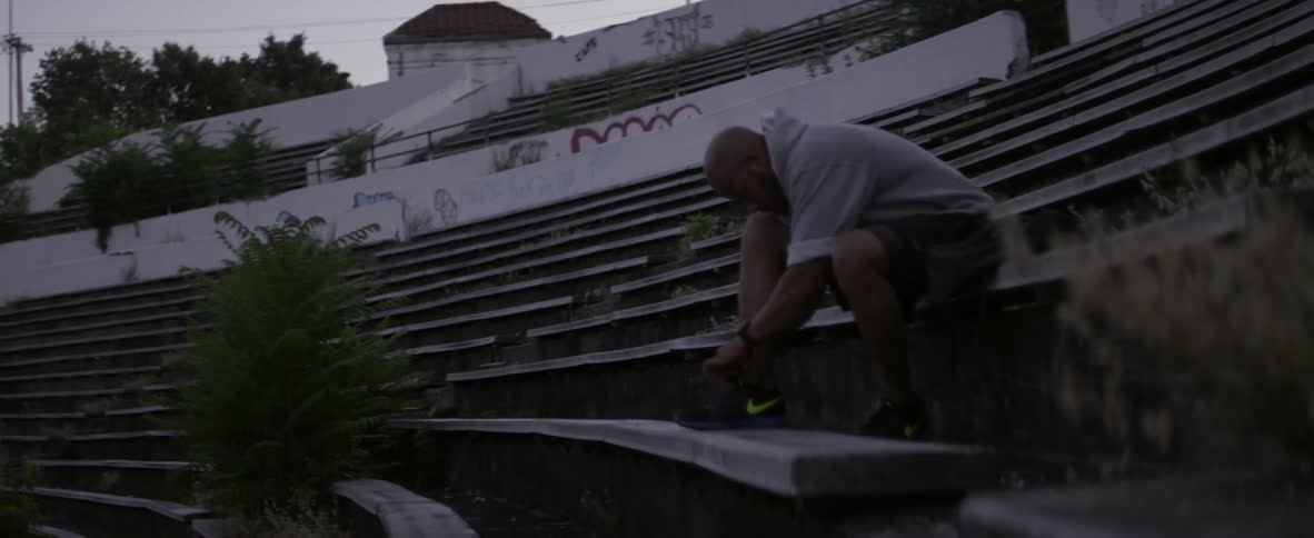 A man sits on the bleachers tying his shoes