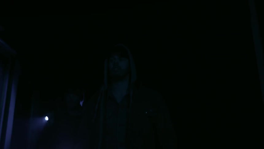 People walk through a dark building with flashlights