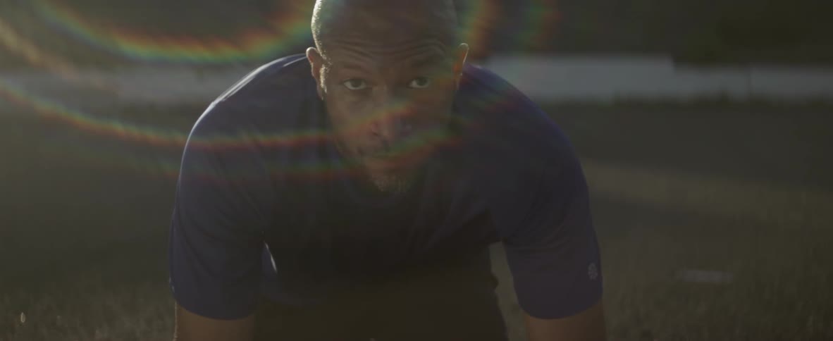 A man crouches on a race track and jumps up