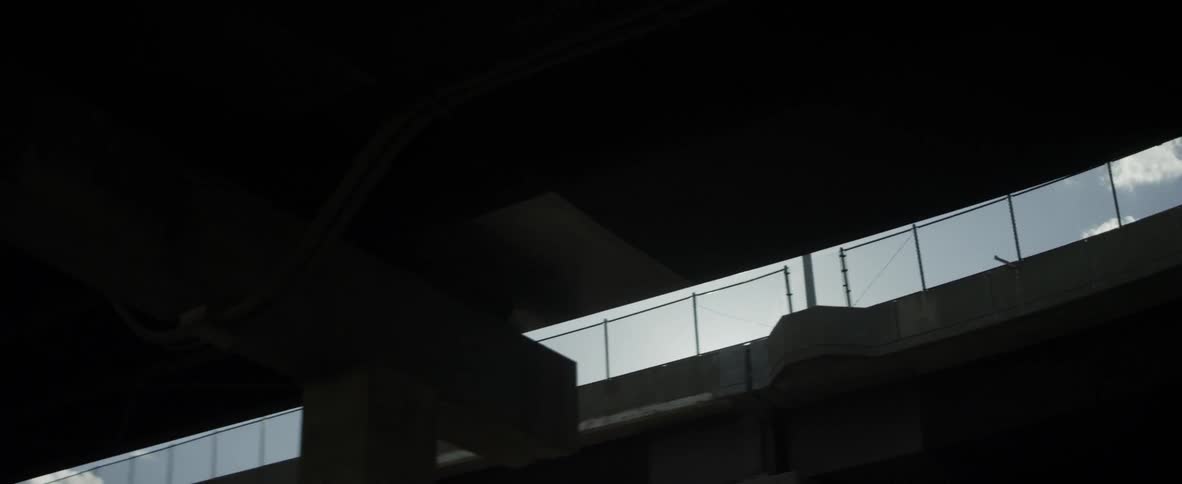 The sun shines through two highway bridges