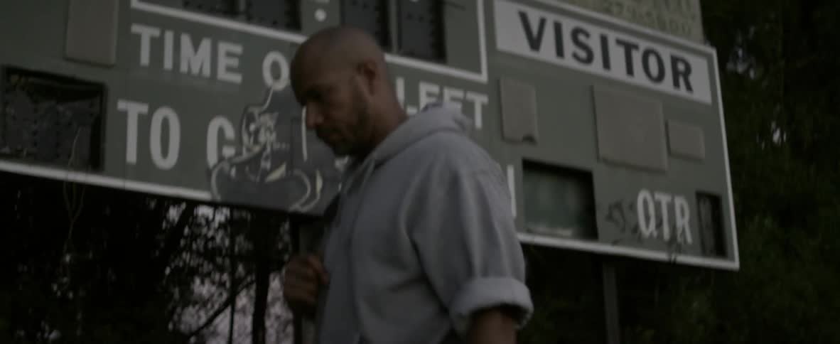 A man is walking past a rundown scoreboard