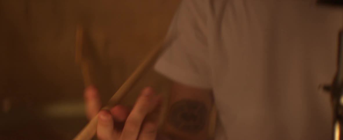 A man is looking down twisting drumsticks in his hand