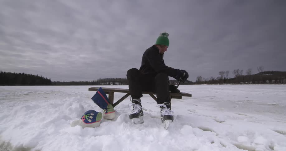 A man puts on his hockey gear and walks off